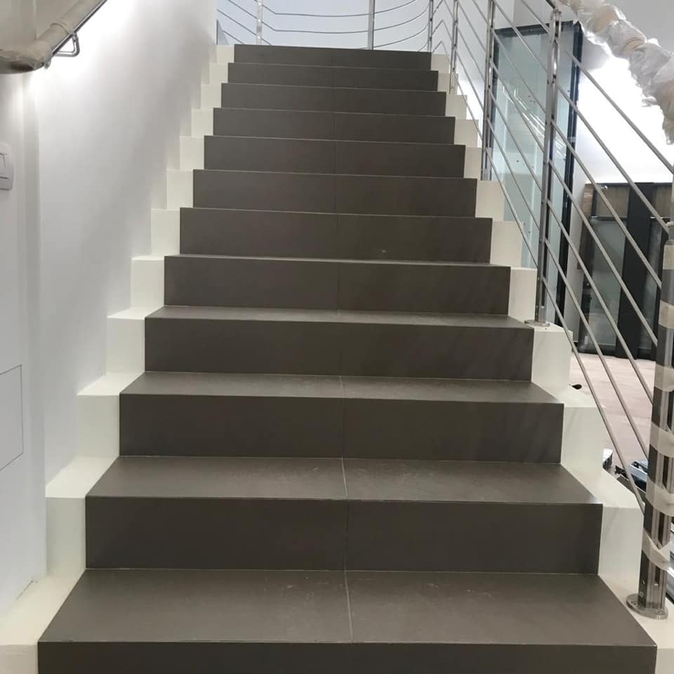 Scala rifinita con gradini grigi e parapetto metallico