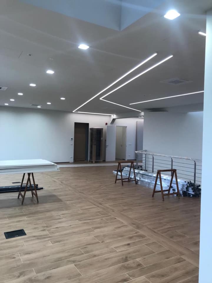 Spazio interno con pavimentazione effetto legno e luci lineari